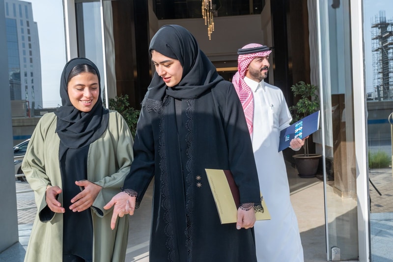 ثلاثة زملاء يخرجون من المبنى وهم يتحدثون