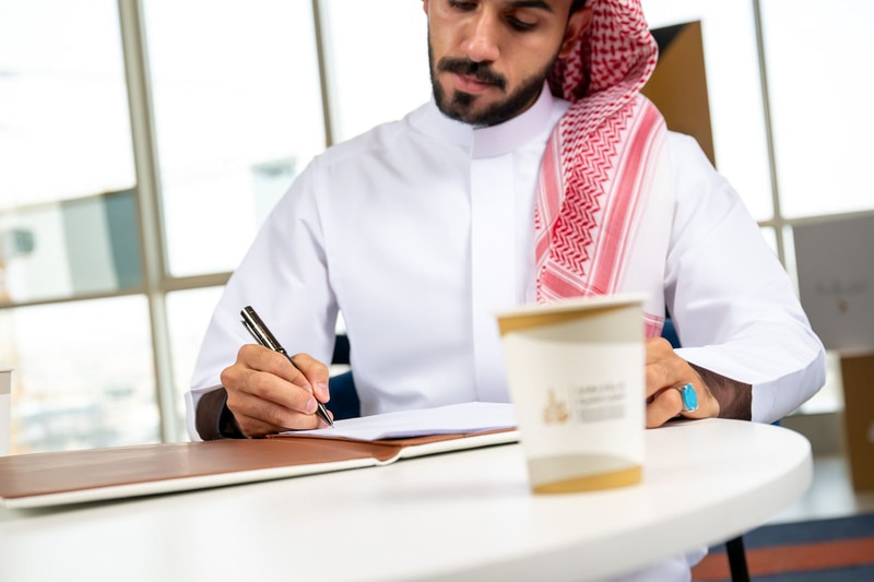 شاب يكتب ملاحظاته بجانب كوب قهوة