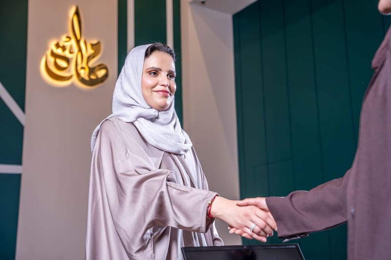 موظفة تصافح زائرًا أمام شعار مهارة
